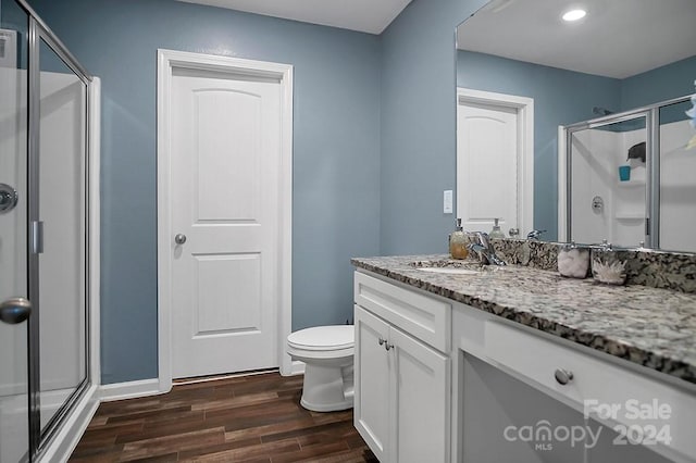 bathroom featuring wood-type flooring, vanity, toilet, and an enclosed shower