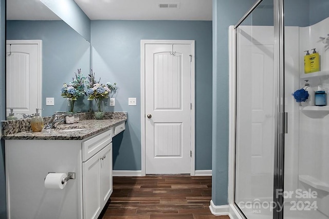 bathroom with wood-type flooring, vanity, and a shower with shower door