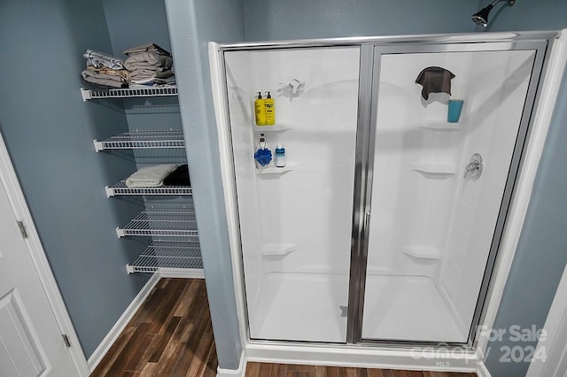 bathroom with wood-type flooring and a shower with shower door