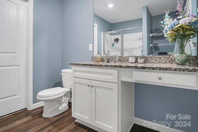 bathroom with wood-type flooring, toilet, vanity, and a shower with shower door