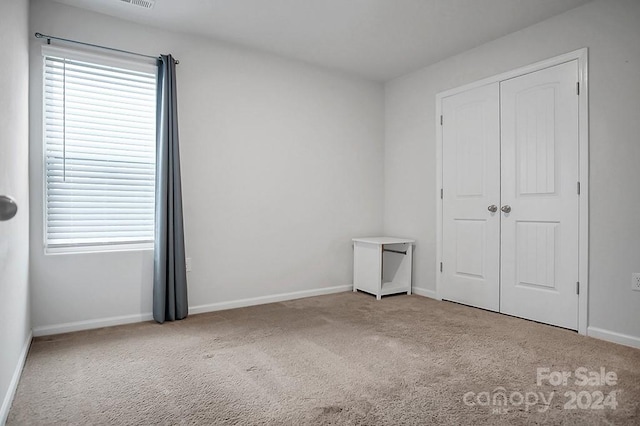 unfurnished bedroom with a closet, multiple windows, and light carpet