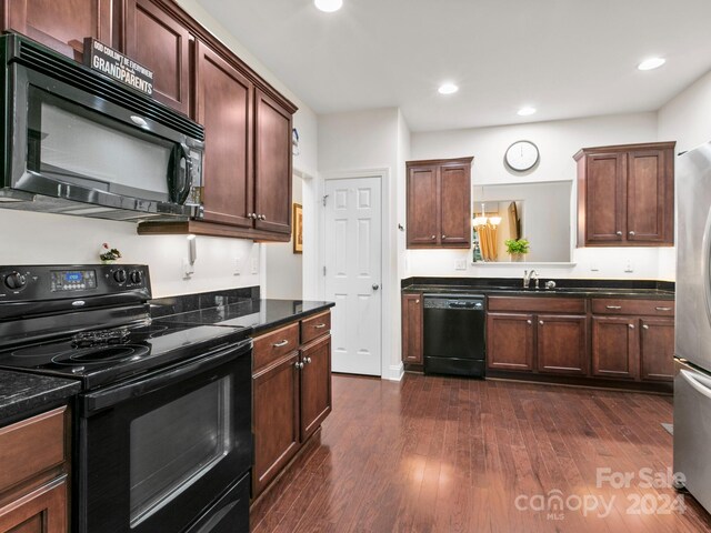 kitchen with sink, dark stone counters, dark wood-type flooring, and black appliances