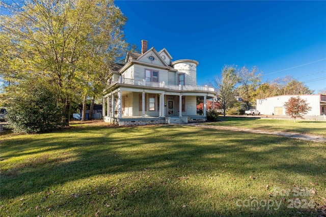 victorian house featuring a balcony, a front lawn, and a porch