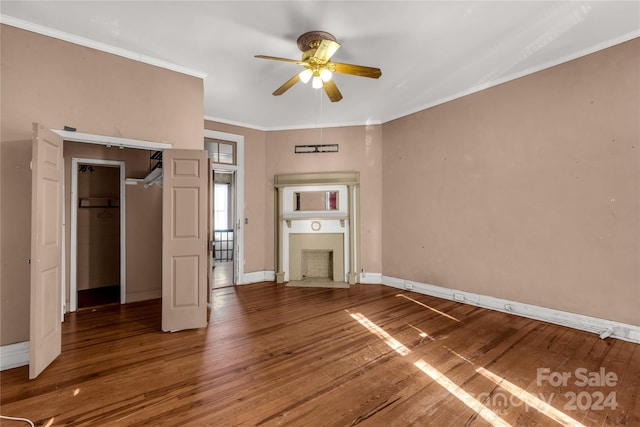 unfurnished bedroom featuring wood-type flooring, a closet, ceiling fan, and crown molding