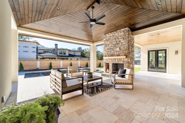 view of patio / terrace featuring an outdoor living space with a fireplace, ceiling fan, and french doors