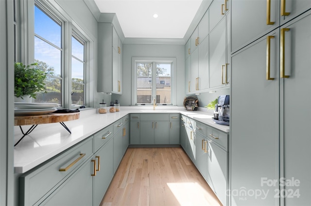 kitchen with sink, built in refrigerator, light wood-type flooring, gray cabinets, and ornamental molding