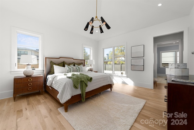 bedroom featuring a chandelier, access to outside, and light hardwood / wood-style flooring