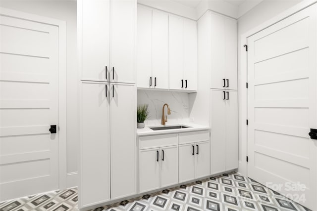 bar with backsplash, sink, and white cabinets