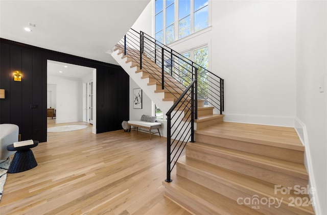 stairs with hardwood / wood-style floors and a towering ceiling