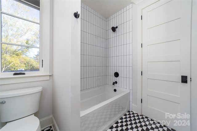 bathroom with tiled shower / bath combo, toilet, and a wealth of natural light