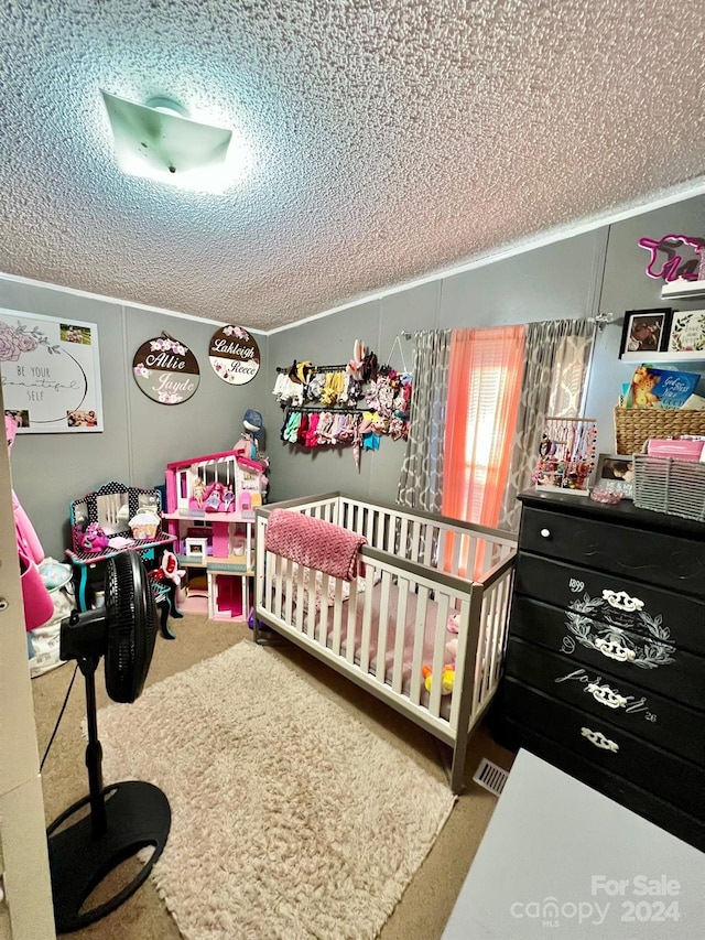 carpeted bedroom featuring a nursery area and a textured ceiling