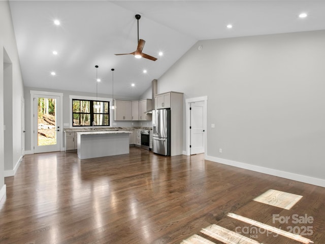 unfurnished living room with ceiling fan, dark hardwood / wood-style flooring, and high vaulted ceiling