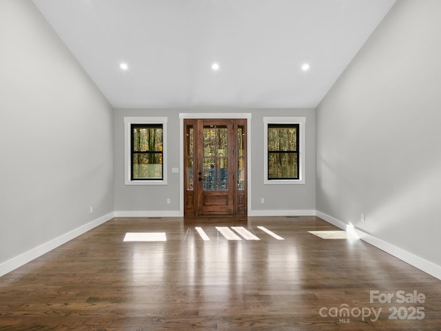 spare room featuring dark wood-type flooring, a wealth of natural light, and vaulted ceiling