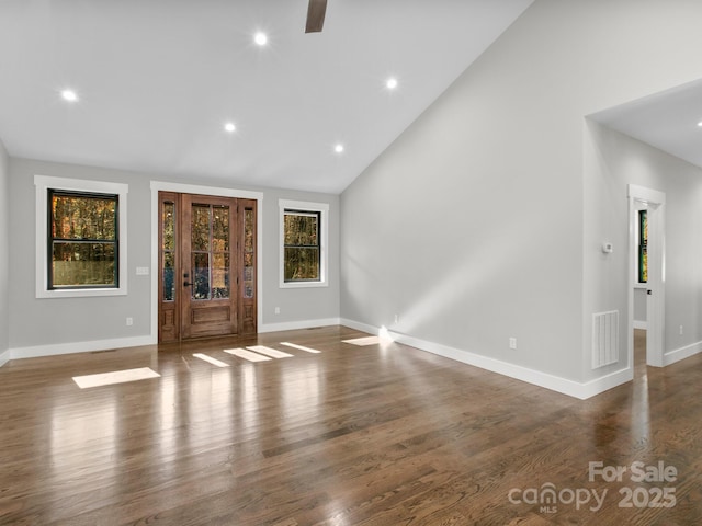 unfurnished living room featuring dark wood-type flooring and high vaulted ceiling