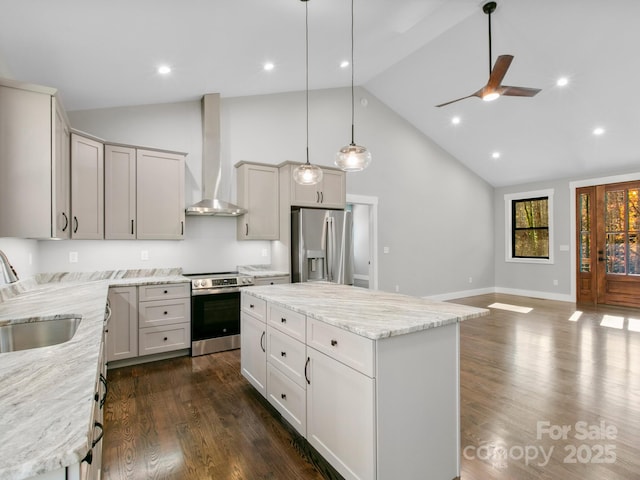 kitchen featuring pendant lighting, sink, stainless steel appliances, a kitchen island, and wall chimney exhaust hood