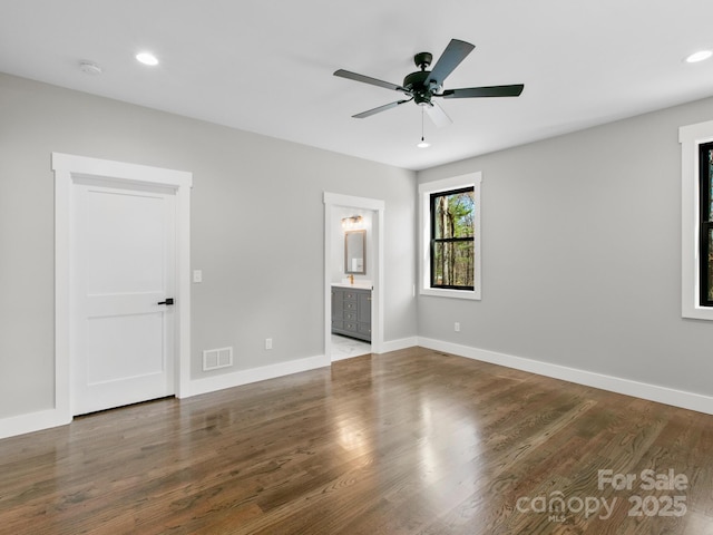 unfurnished bedroom with ensuite bath, dark wood-type flooring, and ceiling fan