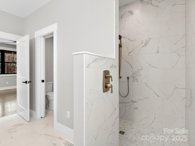 bathroom with tiled shower and toilet