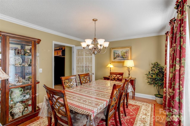 dining room with hardwood / wood-style floors, ornamental molding, a textured ceiling, and a chandelier