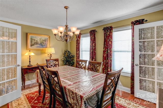 dining room with light wood-type flooring, a textured ceiling, an inviting chandelier, and ornamental molding