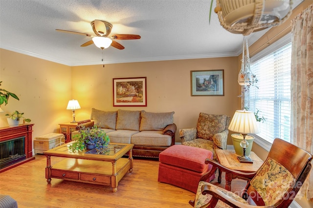 living room featuring ceiling fan, light hardwood / wood-style floors, crown molding, and a textured ceiling