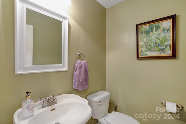 bathroom featuring a textured ceiling, toilet, and sink