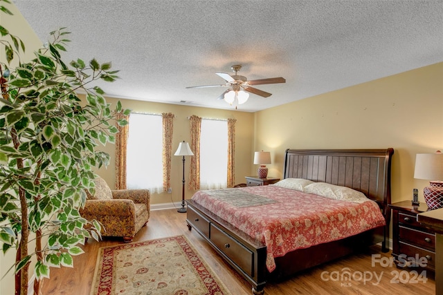 bedroom with ceiling fan, light hardwood / wood-style floors, and a textured ceiling