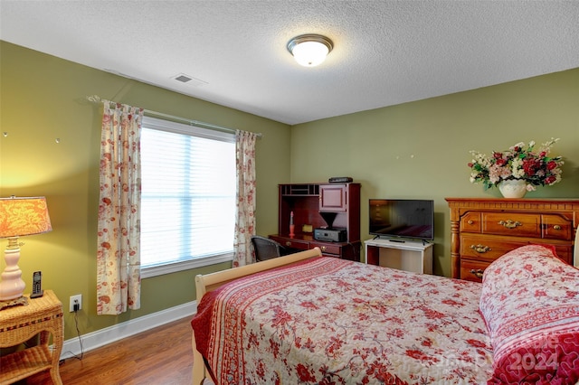 bedroom with hardwood / wood-style flooring and a textured ceiling