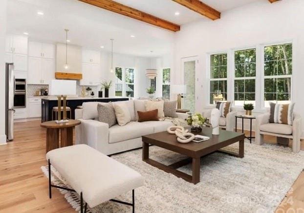 living room with plenty of natural light, beamed ceiling, and light hardwood / wood-style flooring