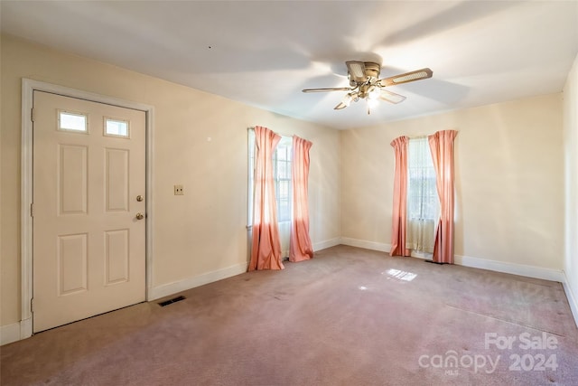 entryway featuring plenty of natural light, ceiling fan, and light colored carpet