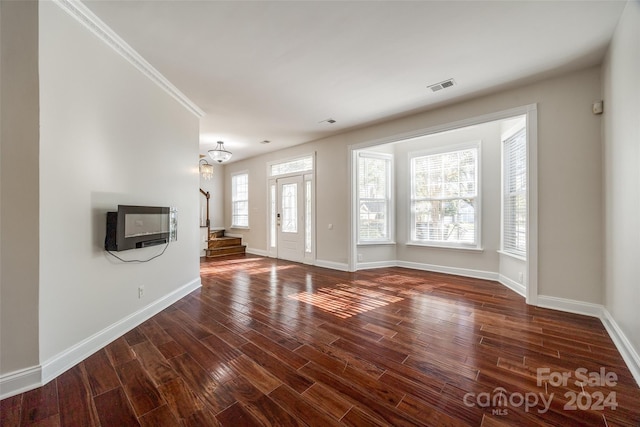 unfurnished living room featuring dark hardwood / wood-style floors, heating unit, ornamental molding, and a notable chandelier