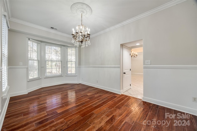 spare room with crown molding, an inviting chandelier, and hardwood / wood-style flooring