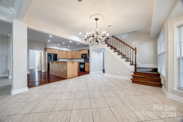 kitchen with a kitchen breakfast bar, black appliances, pendant lighting, a chandelier, and light hardwood / wood-style floors