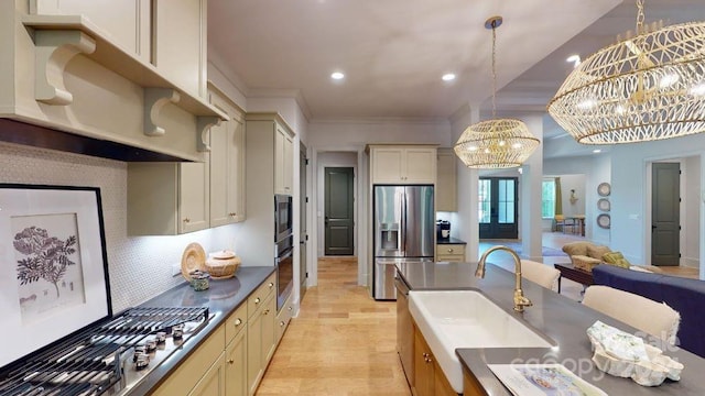 kitchen with cream cabinets, stainless steel appliances, hanging light fixtures, and a chandelier