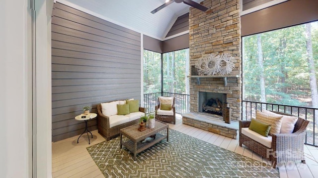 sunroom featuring an outdoor stone fireplace, ceiling fan, and lofted ceiling