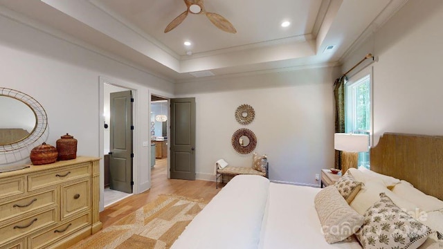 bedroom with a tray ceiling, ceiling fan, light hardwood / wood-style floors, and ornamental molding