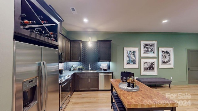 kitchen featuring backsplash, dark brown cabinetry, stainless steel appliances, and light wood-type flooring