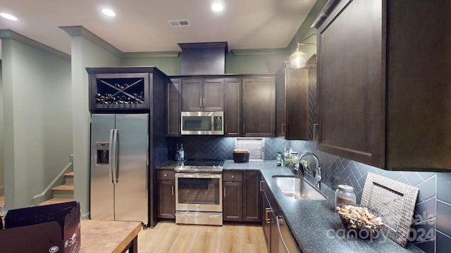 kitchen with backsplash, sink, hanging light fixtures, light wood-type flooring, and stainless steel appliances