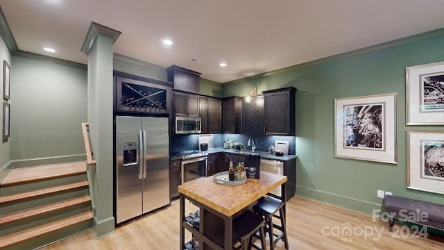 kitchen featuring decorative backsplash, light wood-type flooring, ornamental molding, and stainless steel appliances