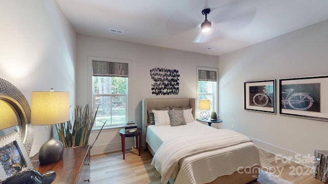 bedroom with light wood-type flooring, multiple windows, and ceiling fan