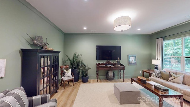 living room with light hardwood / wood-style flooring and crown molding