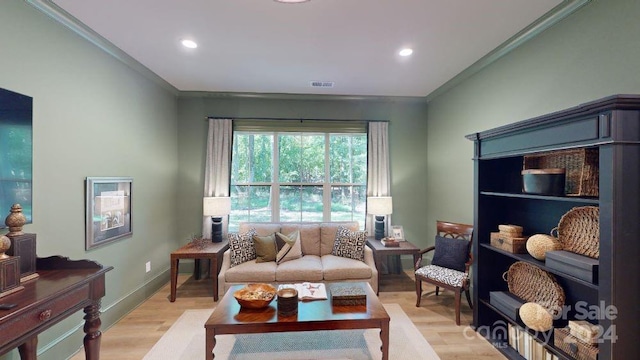 living area with crown molding and light hardwood / wood-style flooring