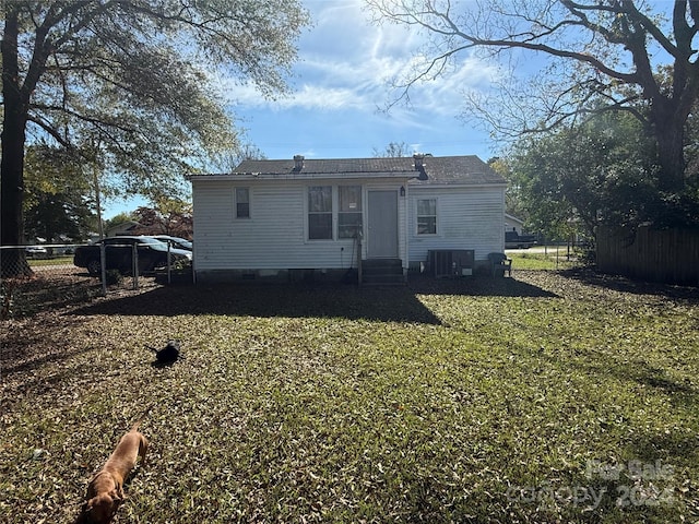 back of property with central air condition unit and a yard