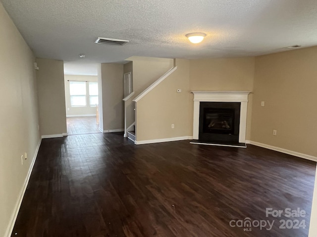 unfurnished living room with dark wood-type flooring and a textured ceiling