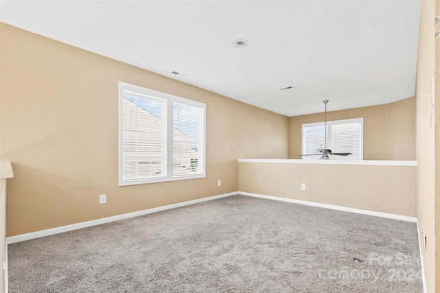 spare room with carpet flooring, a wealth of natural light, and ceiling fan