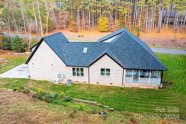 back of house featuring a lawn, a sunroom, and cooling unit