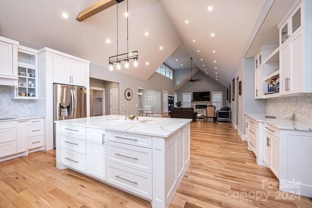 kitchen with a center island with sink, ceiling fan, light wood-type flooring, and white cabinetry