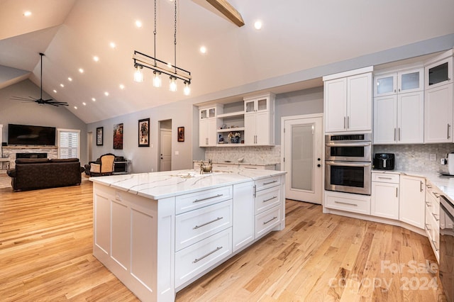 kitchen with white cabinetry, an island with sink, and high vaulted ceiling