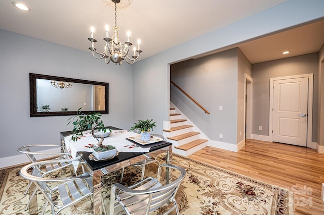 dining area with wood-type flooring and an inviting chandelier