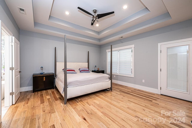 bedroom featuring ceiling fan, light hardwood / wood-style floors, and a raised ceiling