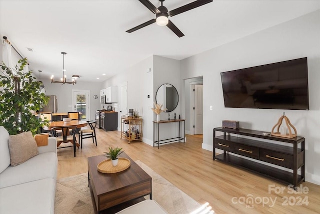 living room with light hardwood / wood-style floors and ceiling fan with notable chandelier